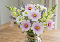 Bouquet of flowers in a glass jar on a wooden table including cosmos daydream