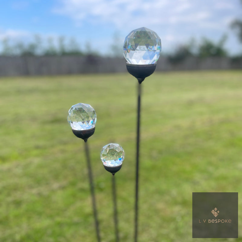 A cluster of three glass garden features among planting