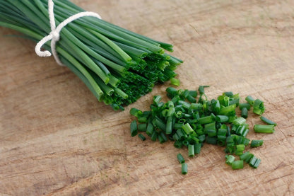 A bundle of fresh chives placed on a wooden tabletop