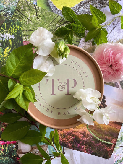 Luxury wax melts packaging surrounded by flowers and greenery, featuring T&amp;P Piglet branding.