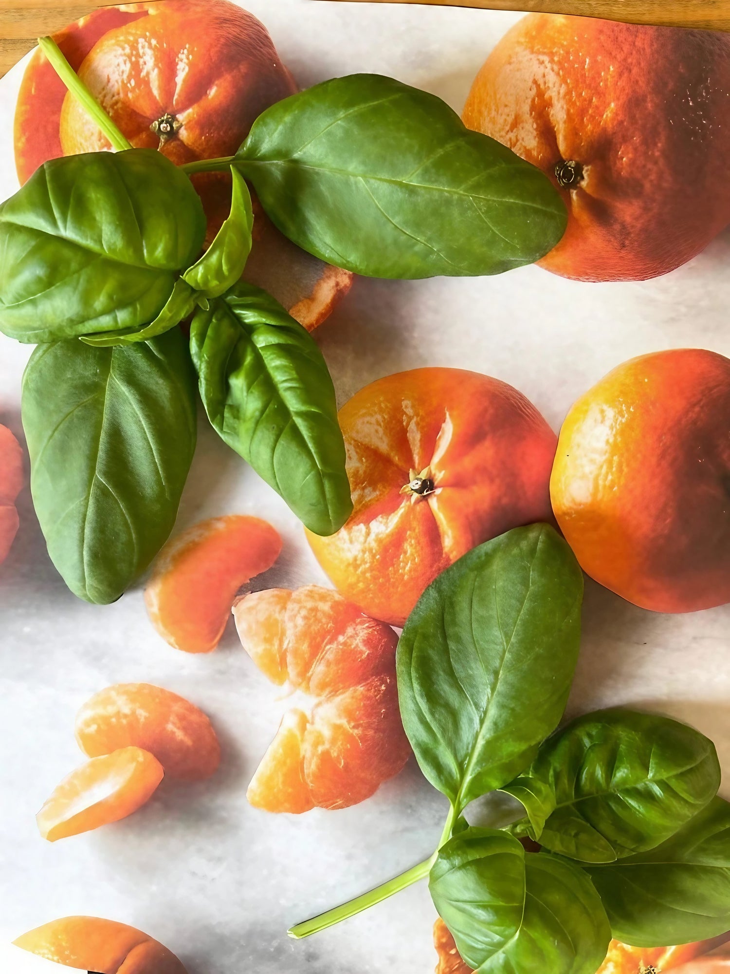 Sliced oranges garnished with Italian basil leaves on a chopping board