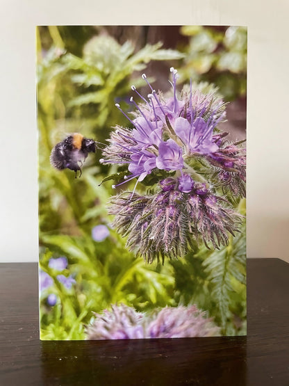 Greeting card featuring a bee buzzing near purple flowers, perfect for thank you notes or gifts.