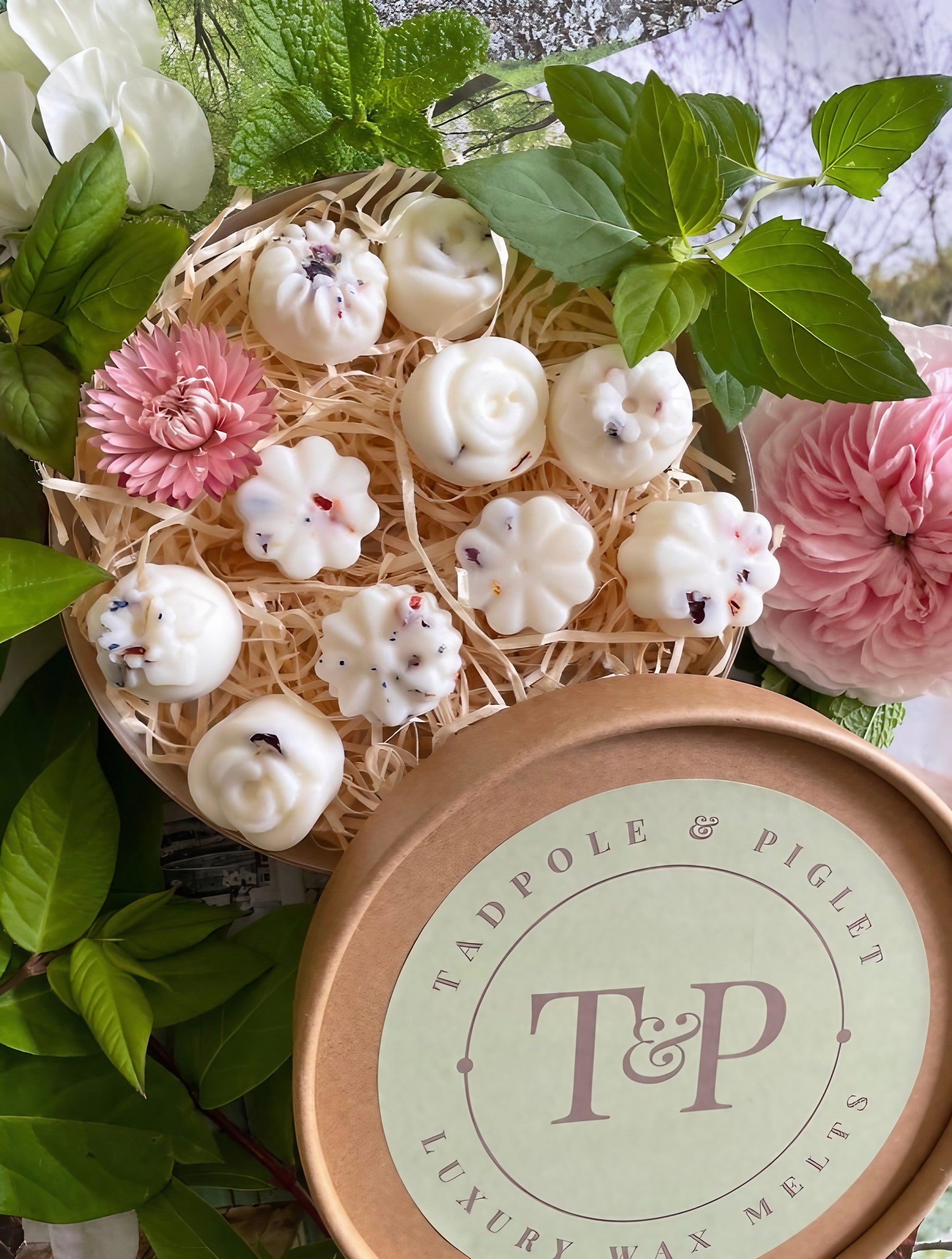 Relax &amp; Unwind pure essential oil wax melts in floral shapes, nestled in natural straw with green leaves and flowers.