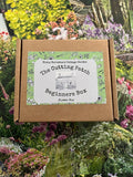 A cardboard box labeled "The Cutting Patch Beginners Flower Box" from Bishy Barnabees Cottage Garden sits on colorful floral backgrounds, featuring a green floral border and cottage illustration—ideal for beginner cut flower growers.
