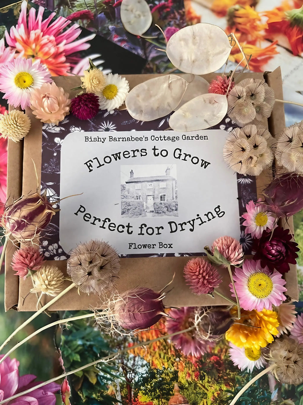 A package of Flowers to Grow - Perfect for Drying by Bishy Barnabees Cottage Garden is shown among dried and fresh blooms in pink, yellow, and cream—perfect for creating sustainable floral decor.