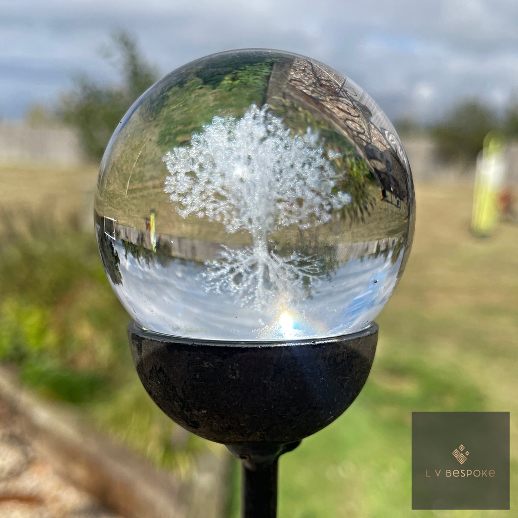 3D orb garden stake with an etched tree of life, standing in a border