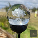 3D orb garden stake with an etched tree of life, standing in a border