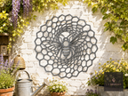 Round metal bee and honeycomb wall plaque on a white brick garden wall