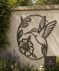 Metal hummingbird and hibiscus wall art on a rendered garden wall