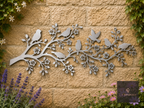 Metal branch wall art with small birds on a stone garden wall