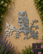 Metal owl perched on a branch wall art on a garden wall