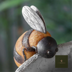 Ceramic bumblebee pot hanger perched on the rim of a planter