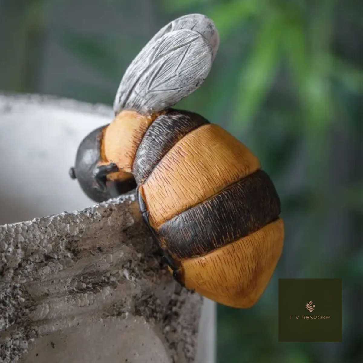 Ceramic bumblebee pot hanger on the edge of a grey pot