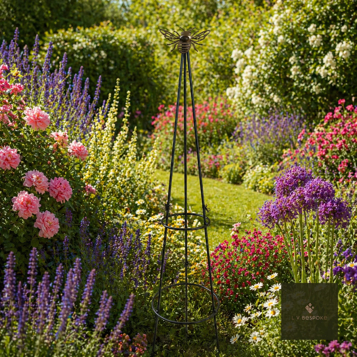 Metal obelisk in a cottage garden border of roses, lavender and alliums