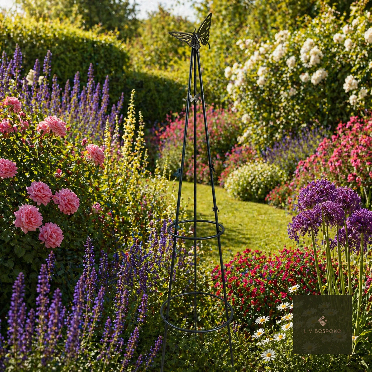 Metal obelisk in a cottage garden border of roses, salvias and alliums