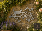 Metal cat on a branch wall art on a stone wall with lavender