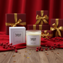 A Tadpole & Piglet Cranberry & Orange Scented Candle with a wooden wick and its box rest on red fabric amid festive berries and red gift boxes with gold ribbons, evoking a cozy holiday vibe.