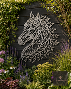 Metal horse head wall art with leafy mane on a dark fence