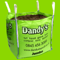 A large green bulk bag labeled Dandy's Topsoil & Landscape Supplies contains Topsoil Welsh Bordermix®. The bag shows contact info, website, and lists gravel, bark, compost, sand, and rock salt on a bright green background.