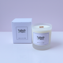 The Tadpole & Piglet Earl Grey & Cucumber Scented Candle, made from natural soy wax, sits in a glass jar beside its matching white box against a pale purple background.