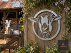 Round metal goat head wall art on a wooden fence