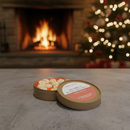 A round tin of assorted popcorn sits open on a stone surface, while Tadpole & Piglet Gingerbread Botanical Wax Melts fill the air with a warm scent. In the background, a glowing fireplace and decorated Christmas tree create cozy holiday vibes.