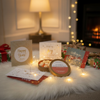 A cozy scene with Tadpole & Piglet's Gingerbread Botanical Wax Melts, New Year cards showing cheerful 2024 messages, wrapped gifts, and fairy lights on a fluffy rug by the fireplace and a glowing lamp.