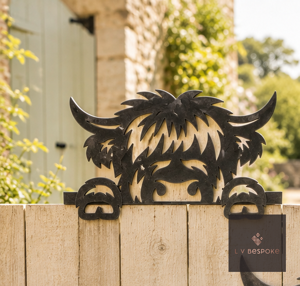 Metal Highland cow peeking over a wooden fence