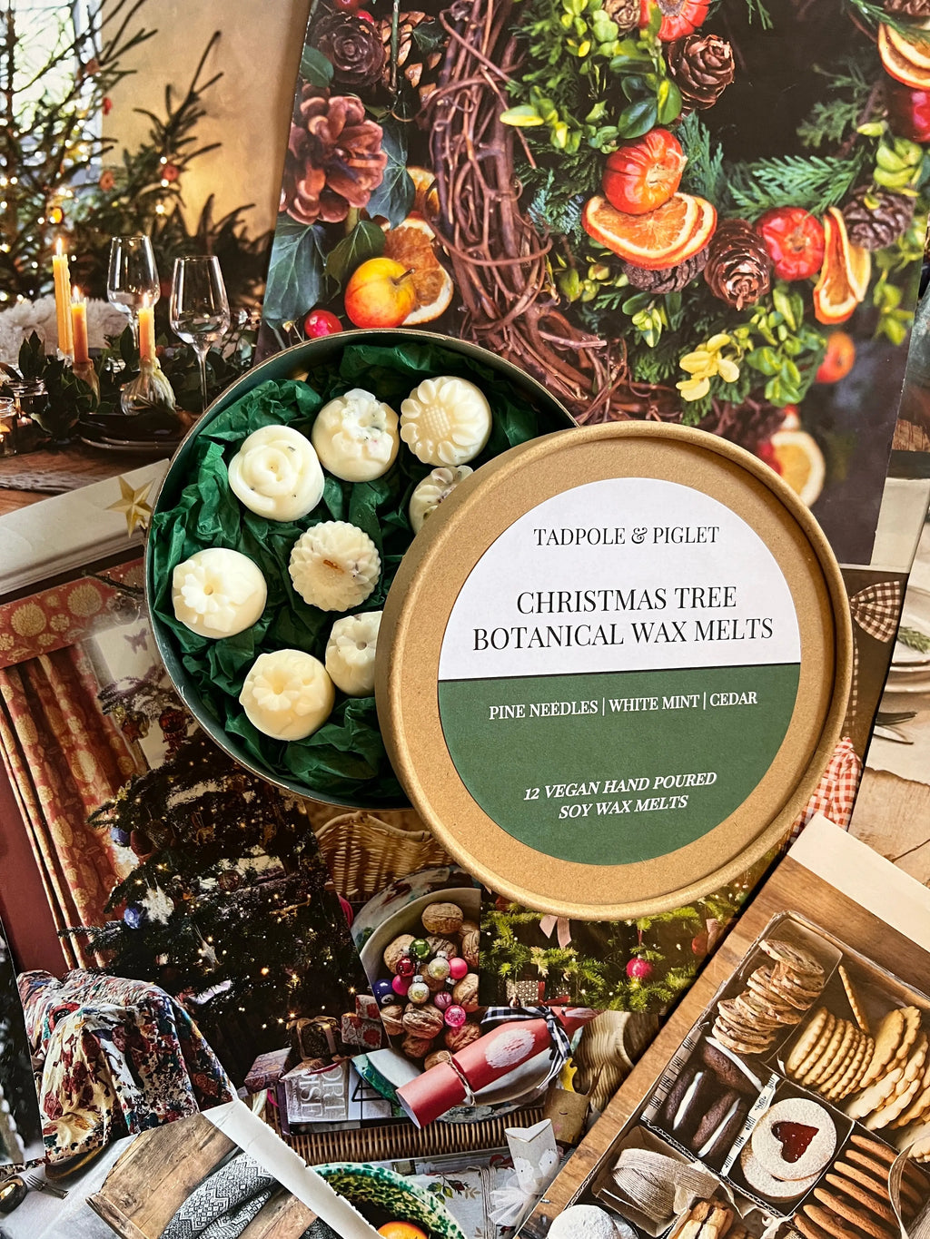 An open Tadpole & Piglet Christmas Tree Botanical Wax Melts tin reveals white Nordmann Fir melts, resting on festive holiday images with decorated trees, candles, and cozy interiors.