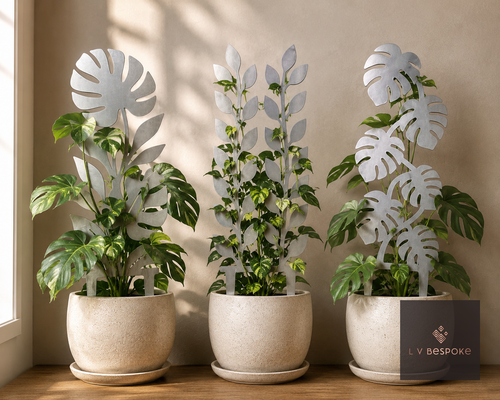 Three metal indoor plant supports with leaf designs in white pots