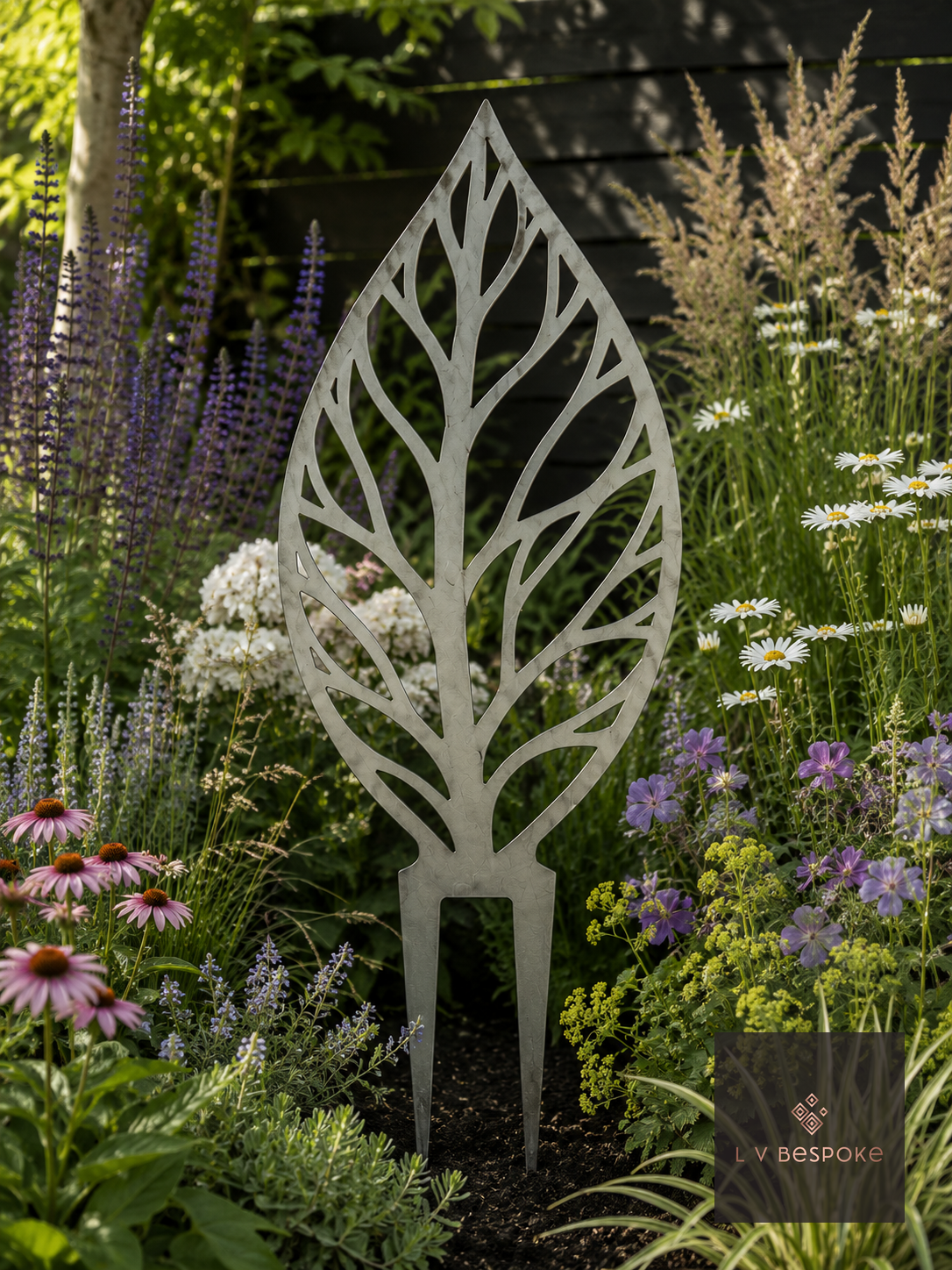 Metal leaf-outline garden stake in a flower border