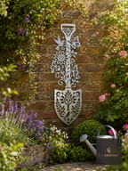 Metal spade-shaped floral wall plaque on a brick garden wall