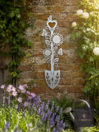 Metal spade-shaped floral wall plaque on a brick garden wall