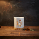 The Tadpole & Piglet White Mandala Cut Out Wax Burner, glowing on its wooden base, sits on a rustic wood surface with Botanical Wax Melts and melted wax beside it against a dark textured background.