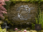 Metal koi fish wall art on a stone wall above a pond