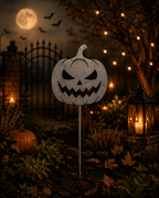Metal jack-o'-lantern pumpkin garden stake in a night-time Halloween scene