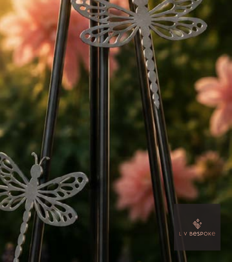 Metal dragonfly obelisk tops among pink flowers