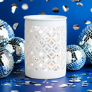 The White Matte Lattice Cut Wax Burner by Tadpole & Piglet glows softly amid disco balls and silver confetti on a blue background—an ideal minimalist home fragrance accent.