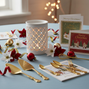 A festive table features Tadpole & Piglet's White Matte Lattice Cut Wax Burner, warm lights, gold cutlery, Christmas cards, red and white poinsettias, baubles, and a light blue tablecloth for a cozy minimalist home fragrance.