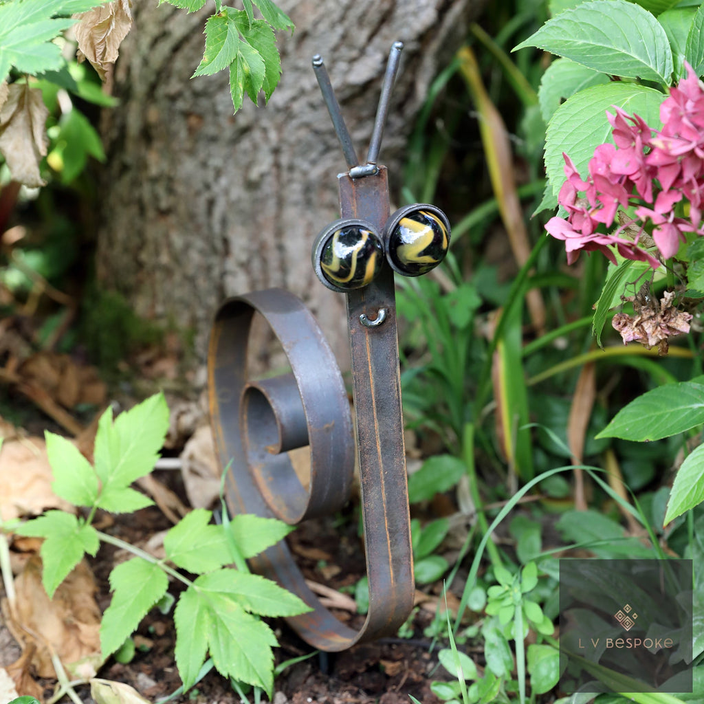 Steel snail with dark spotted marble eyes in a shady border