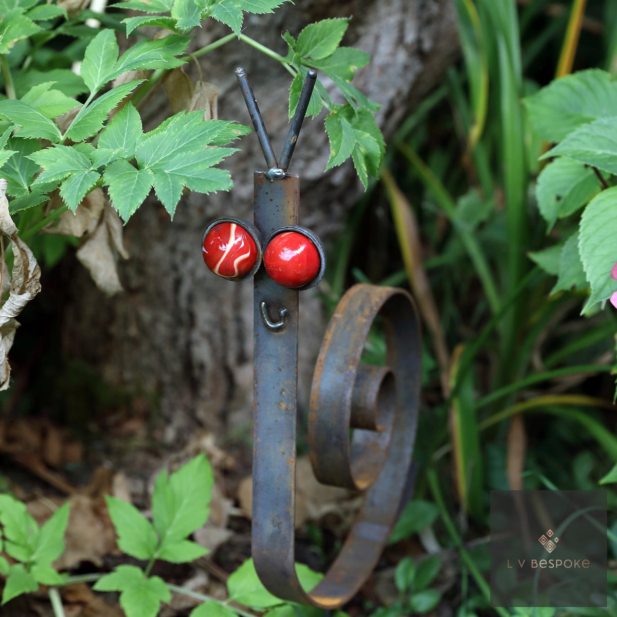Steel snail with red marble eyes on green ground cover
