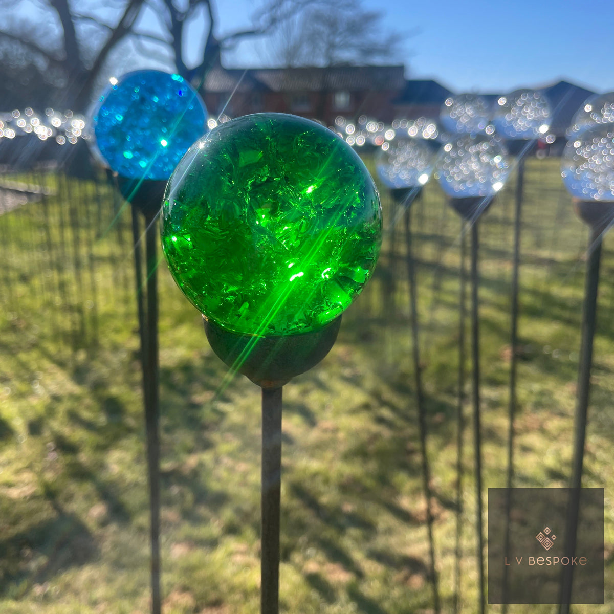 Green and turquoise glass-topped stakes among rows of clear glass stakes