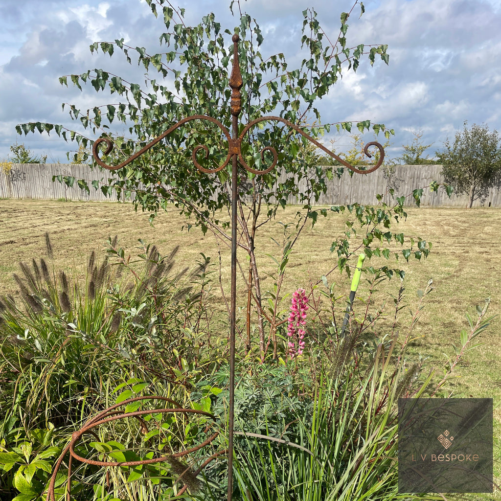 Two-arm bird feeding stake in a border with fields behind