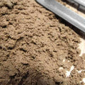 Close-up of a pile of Rootzone Sand and Soil Mix by Dandy's Topsoil & Landscape Supplies, with part of a metal tool visible—commonly used for lawn drainage projects.