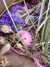 A close-up of Bishy Barnabees Cottage Garden's Dried Flower Craft Box shows a bouquet with purple, white, and pink dried flowers plus grasses on pink tissue—ideal for your next craft project or use as dried flowers for crafts.