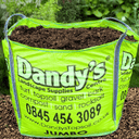 A large bright green bag labeled Dandy's Topsoil & Landscape Supplies is filled with brown Compost Wintermix Garden Mulch. The bag displays a phone number, website, and advertises mulch among other landscape materials.