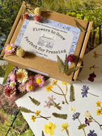 A Flowers to Grow...Perfect for Pressing box by Bishy Barnabees Cottage Garden is surrounded by pressing flowers, dried ferns, and cards with pressed flower art, all arranged on a floral-themed background.