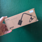 Hand holding a Grow Gang Stelo lamp stand box in black against a green wall
