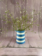Gypsophila Pink in a blue and white striped vase against weathered pink wood