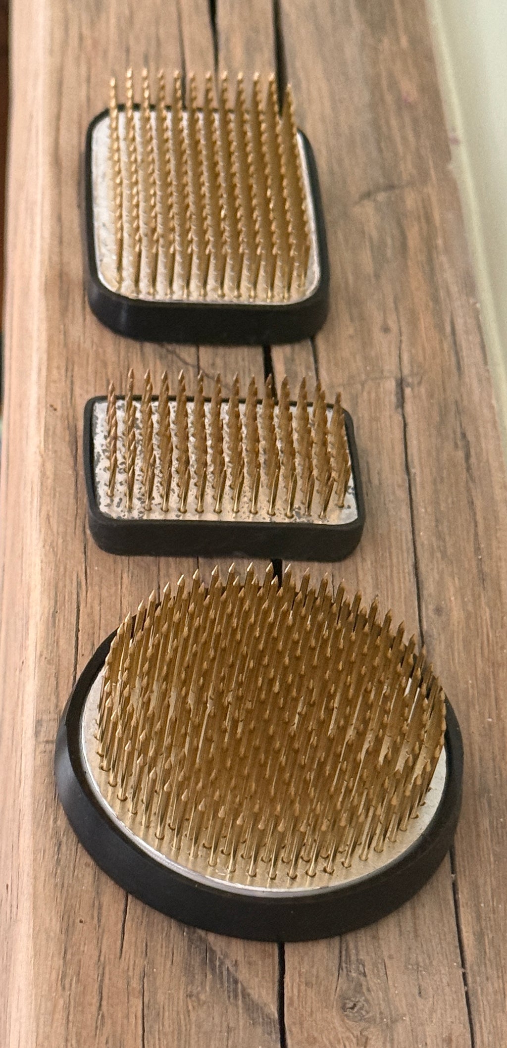Kenzan Flower Frogs in three sizes seen from above on a wooden board